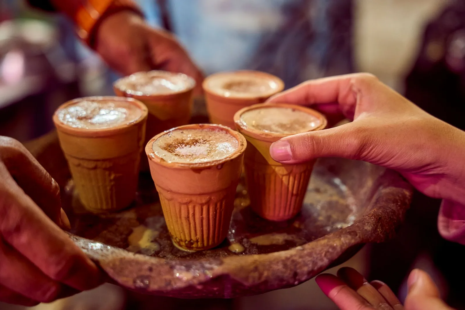 Chai au lait mousseux servi dans des gobelets en terre cuite sur un plateau
