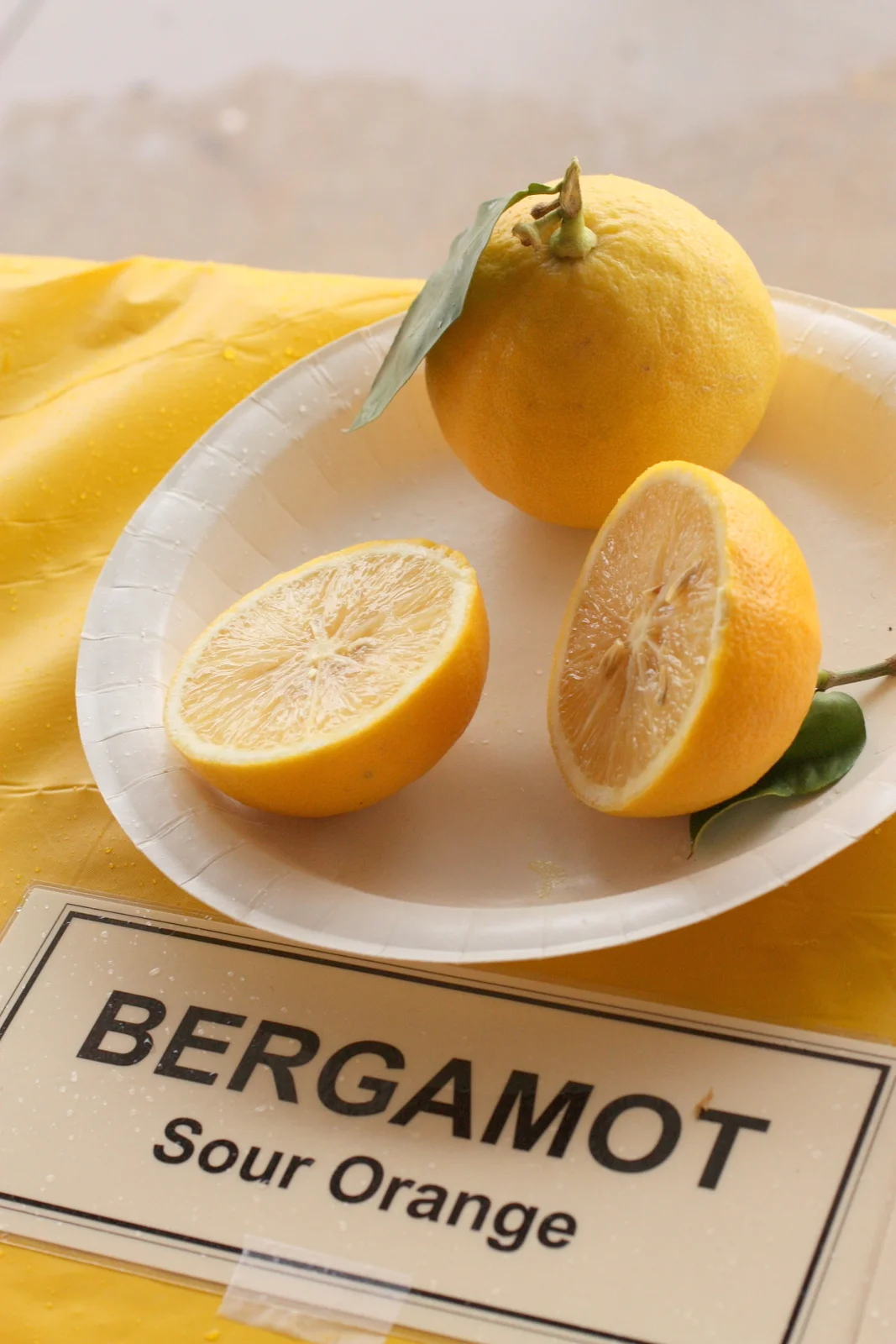 Bergamotes entières et coupées en deux dans une assiette, le fruit qui parfume l'Earl Grey